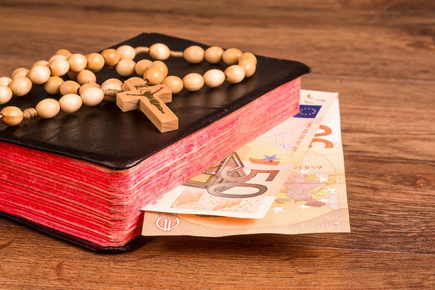 Foto: Gebetsbuch mit Geldscheinen und Kruzifix